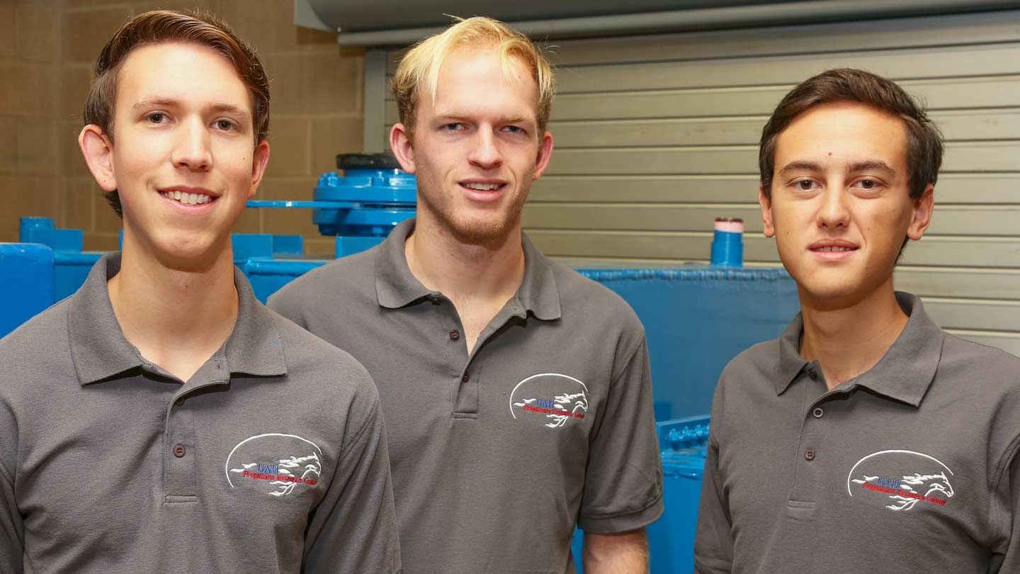 three students stand next to a machine