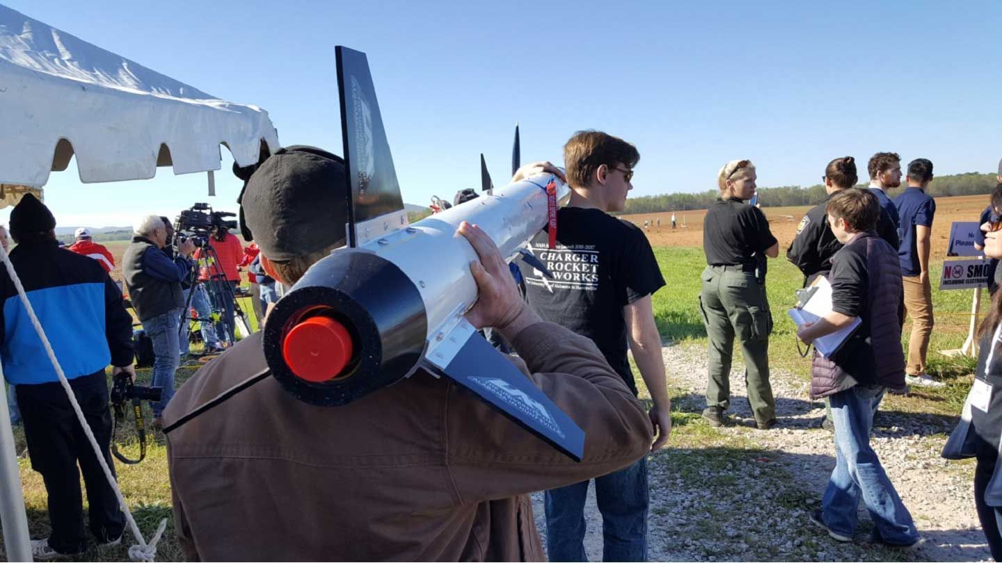 two people carry a rocket on their shoulders