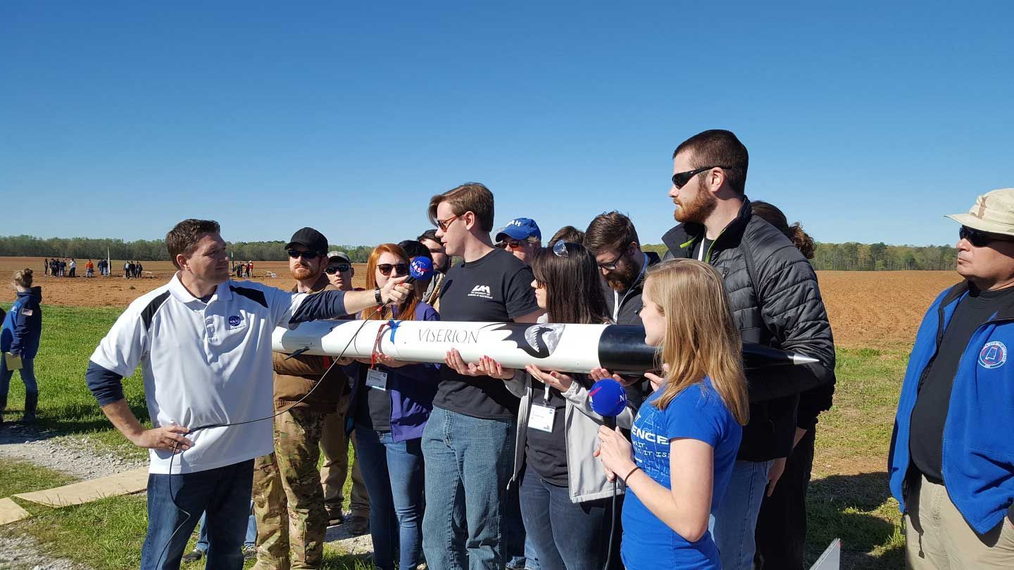 students move a rocket in a field