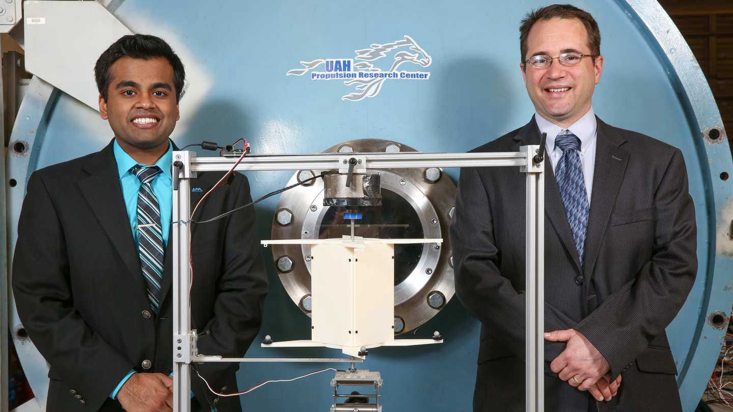 two men stand beside a large apparatus