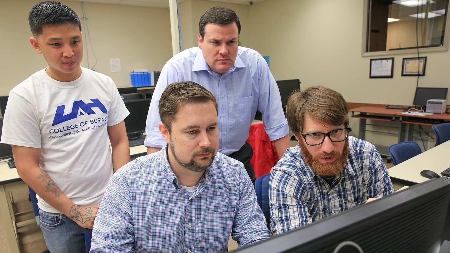 3 men examine a screen