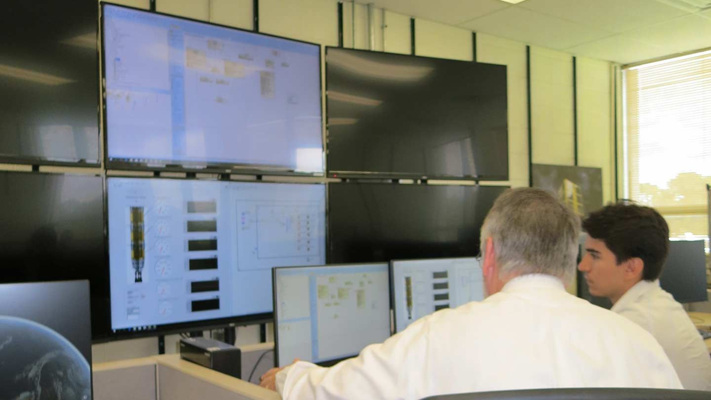 men examine screens of data