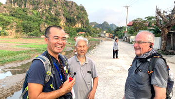 OLLI at UAH member Cliff Lanham (right) and tour guide Thuyen Nguyen (left) speaking with a local near Hoi An, Vietnam, in October 2019.