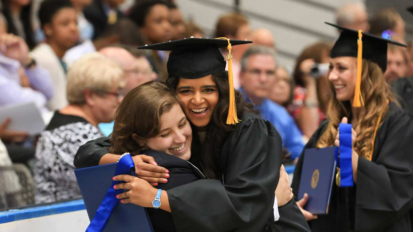 Graduates hugging at commencement