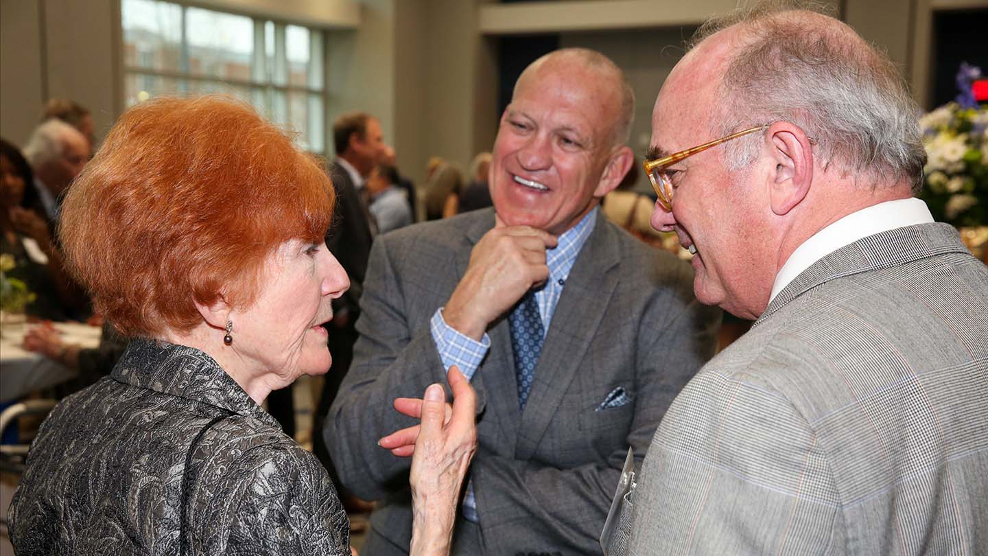 guests smiling and conversing with uah interim president dr. karr