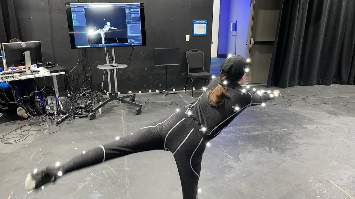 student posing with special gear and computers in UAH motion capture lab