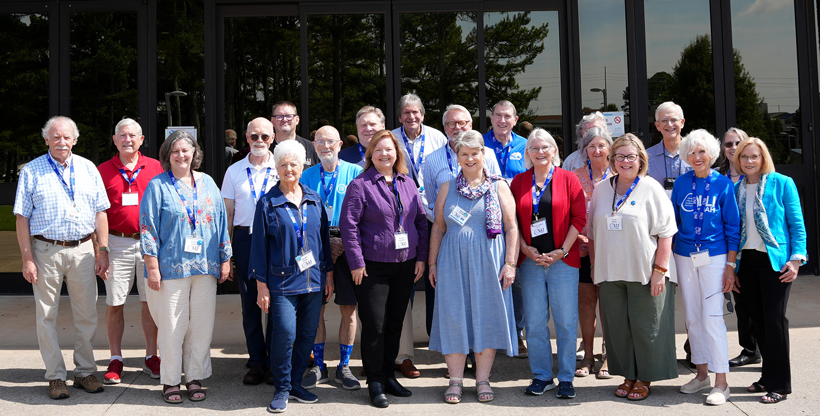 A group of 20 individuals standing in front of the entrance to a building.