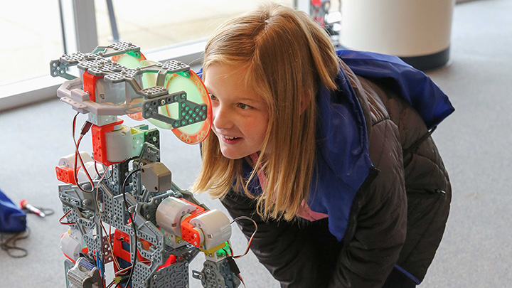 girl examining a robot ?>