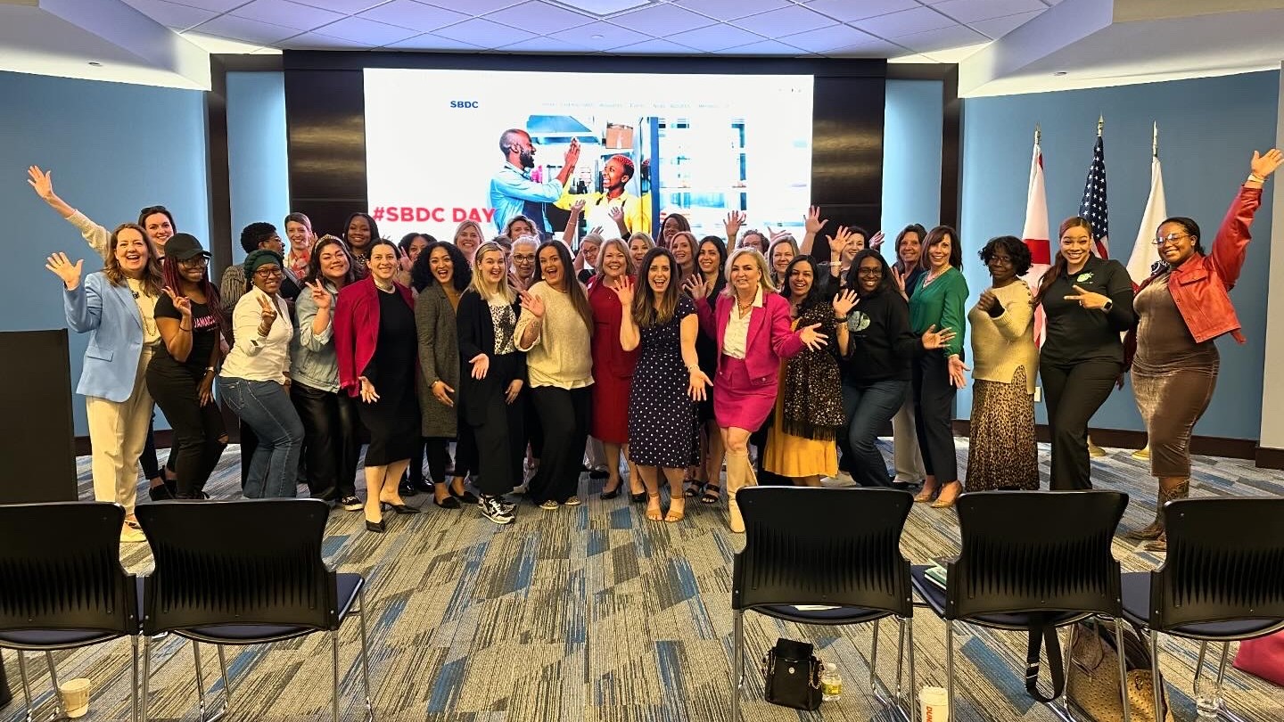 A diverse group of women in a conference room, actively participating in a program to enhance small business