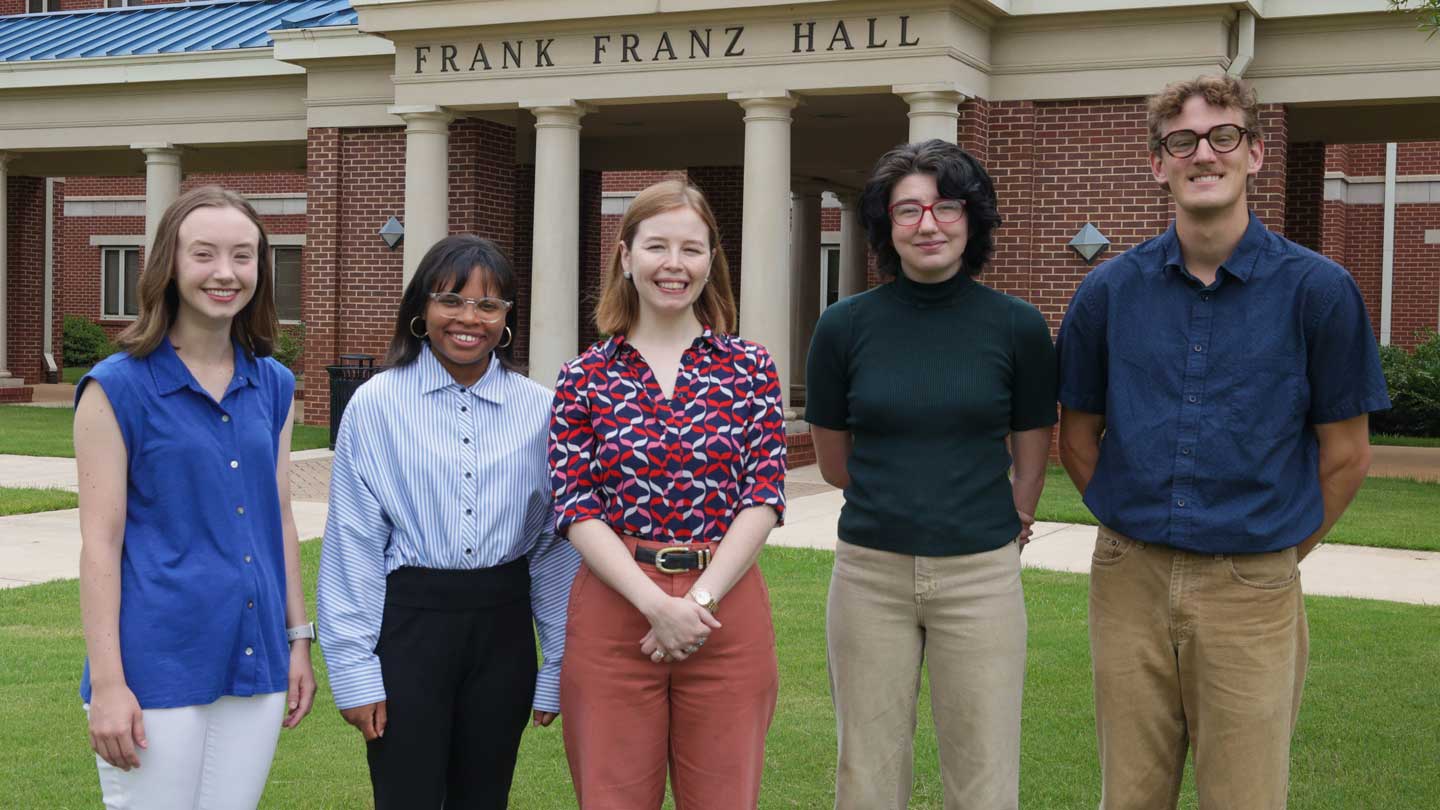 Four of the nine UAH recipients of national scholarships and fellowships in the spring 2025 semester stand beside their advisor on the lawn in front of Frank Franz Hall, home of The University of Alabama in Huntsville Honors College.