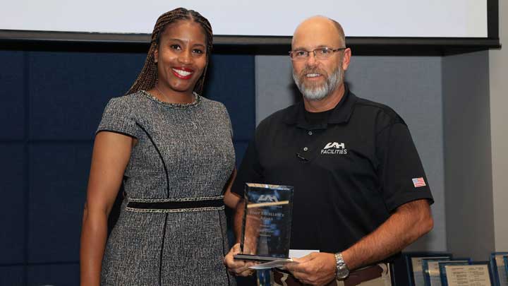 Dr. Kristy Lee, left, presents the Staff Excellence Award to John Dant.