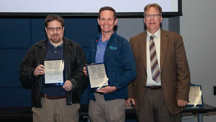 Dr. Aaron Werth, left, and Dr. Tommy Morris, center, receive patent award plaques from Dr. Robert Lindquist.
