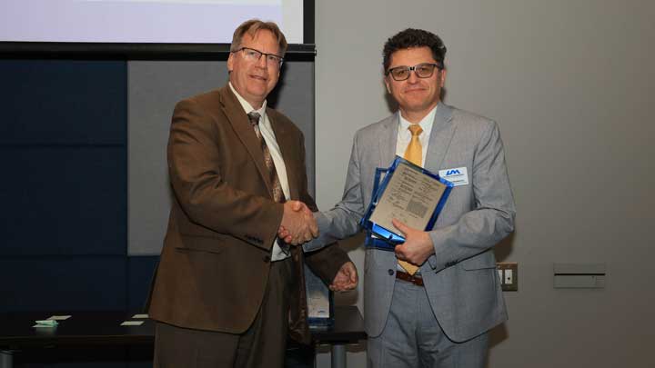 Dr. Robert Lindquist, left, presents patent award plaques to Dr. Aleksandar Milenkovic.