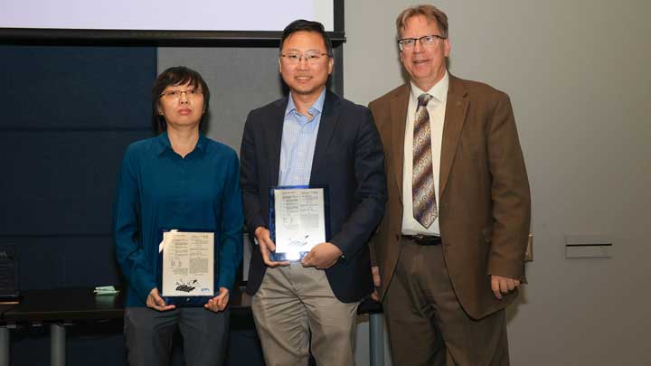 Dr. Tingting Wu, left, and Dr. Yu Lei receive patent award plaques from Dr. Robert Lindquist