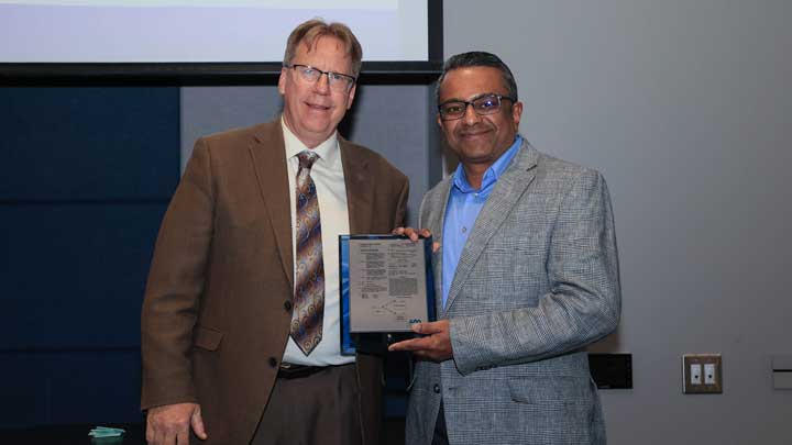 Dr. Robert Lindquist, left, presents a patent award plaque to Dr. Tathagata Mukherjee.