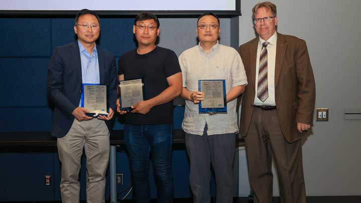 Dr. Yu Lei, Dr. Moonhyung Jang and Dr. Gang Wang, left to right, receive patent award plaques from Dr. Robert Lindquist.