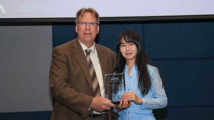 Dr. Lingling Zhao, right, receives the University Researcher of the Year Award from Dr. Robert Lindquist.