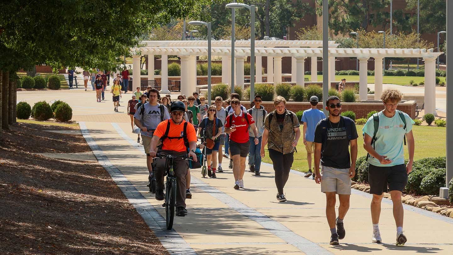 Students walking to class outside on a greenway.