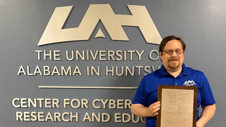Dr. Aaron Werth displays his patent at the UAH Center for Cybersecurity Research and Education.