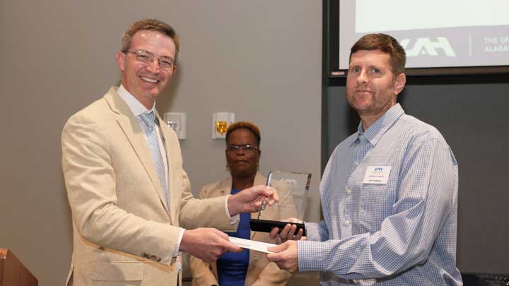 Brad Cooper, left, interim chief financial officer, presents the Staff Excellence Award to Jeffrey Champoux