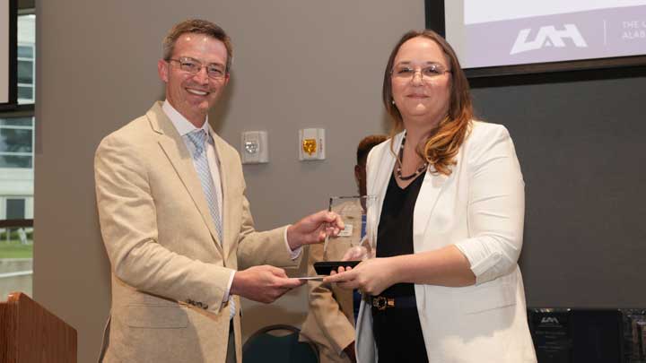 Brad Cooper, left, interim chief financial officer, presents the Staff Excellence Award to Kathleen Sobai. 