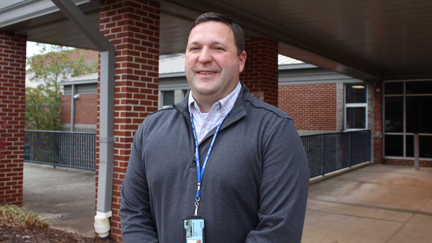 Bryan Rogomentick stands at the front entrance to Bob Jones High School, where he’s spent the fall 2025 semester as a teaching intern.