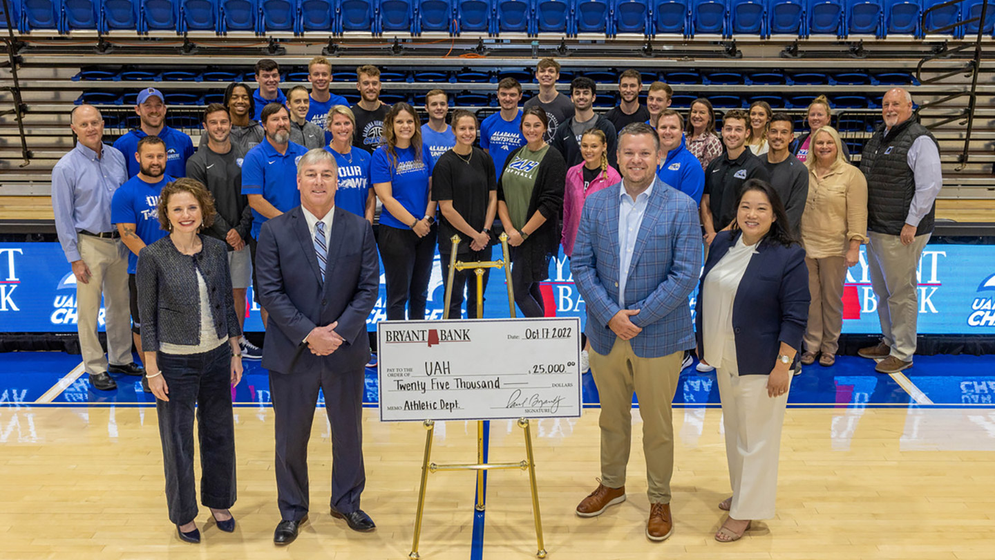 a group of people pose in a gymnasium with a check