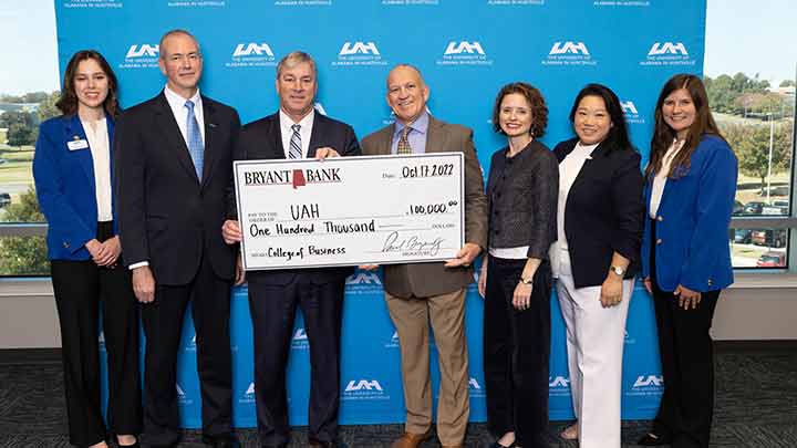 six individuals stand with a check held in the middle