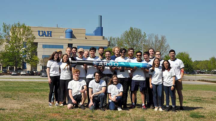 The Charger Rocket Works student team posing new a model rocket