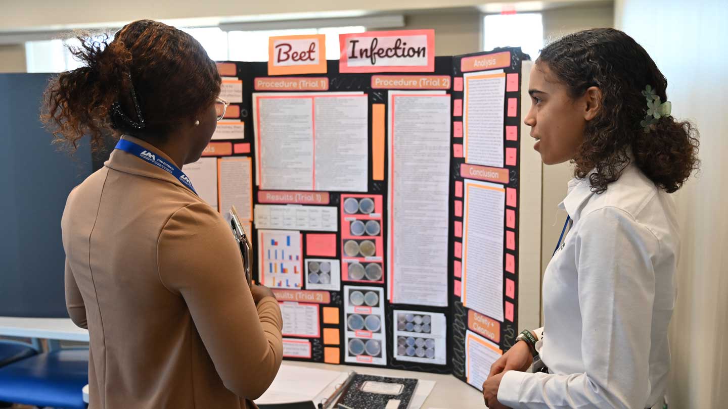 Brianna Wilkinson, right, a current sophomore at St. John Paul II Catholic High School, speaks to Jane-Frances Chinenye Ojobor, a Ph.D. candidate at UAH and one of the event judges, about her project “Beet Infection.”