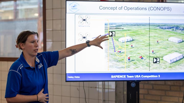 Woman presents a drone operation concept on a large screen labeled “Concept of Operations (CONOPS).