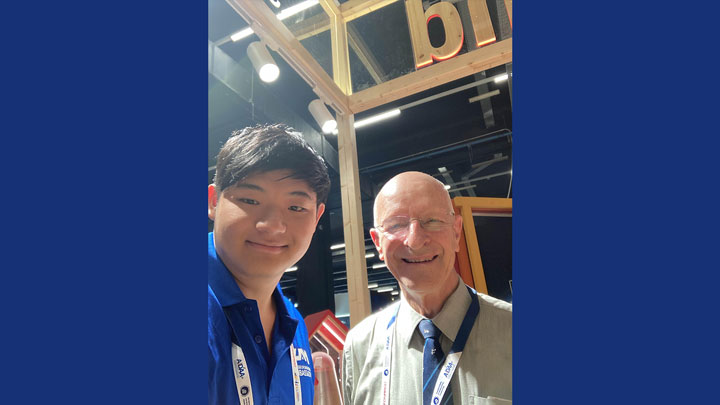 Two individuals in blue shirts with badges at an event with a 'BIT' sign in the background.