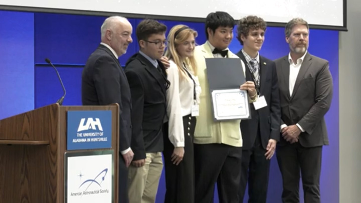 Group of people at a ceremony with one holding a certificate, at the University of Alabama in Huntsville.
