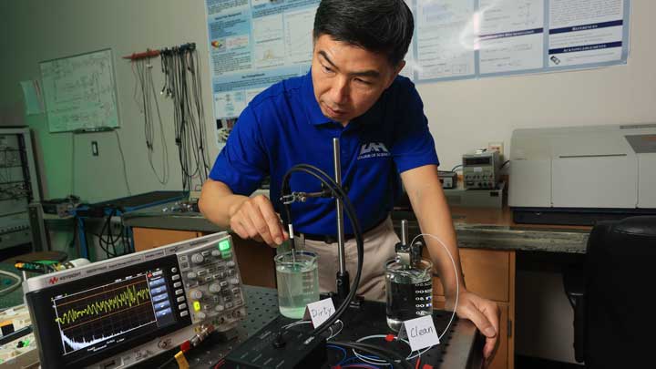 Person in a lab setting conducting an experiment with liquids labeled Dirty and Clean using scientific equipment and monitoring data.