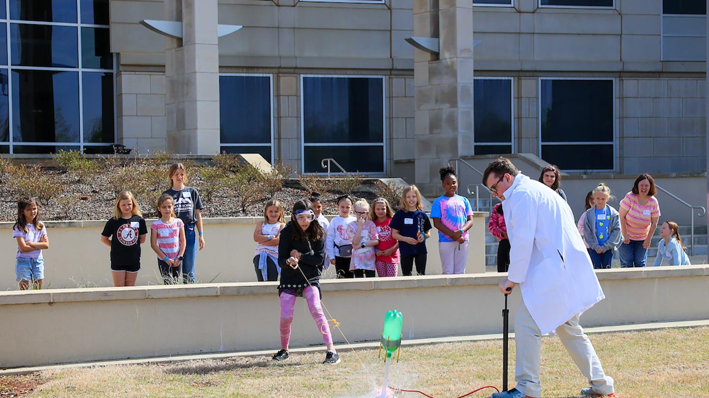 Plastic soda bottles illustrate the principles of propulsion during an outdoor “rocket” launch at Girls in Science and Engineering Day