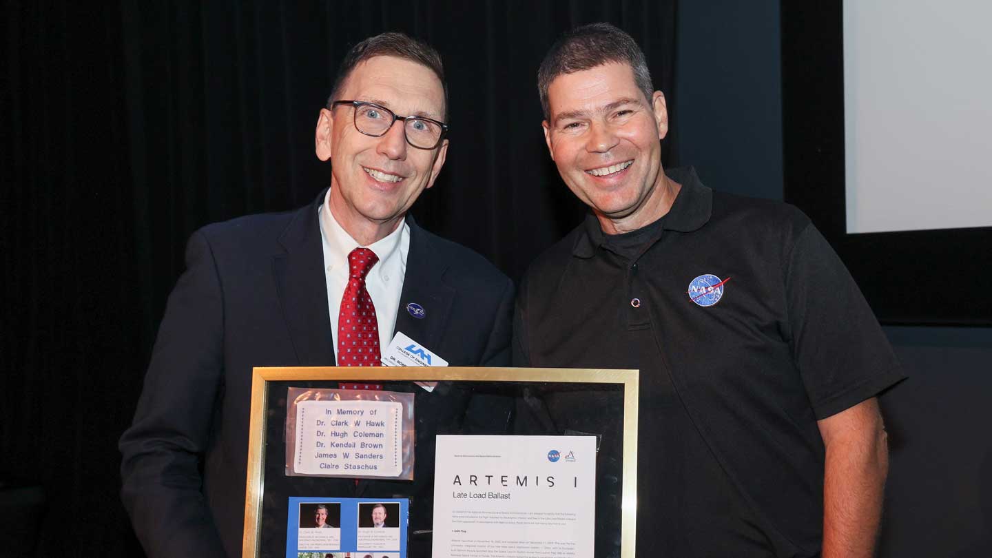 Dr. Robert Frederick, director of the UAH Propulsion Research Center, presents Dr. John Blevins with a flag that was flown around the moon on the Artemis I mission.