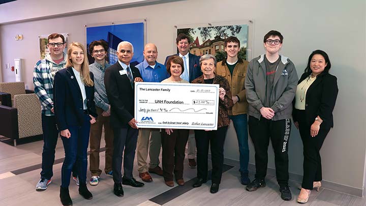 a group of people stand in front of a large check ?>