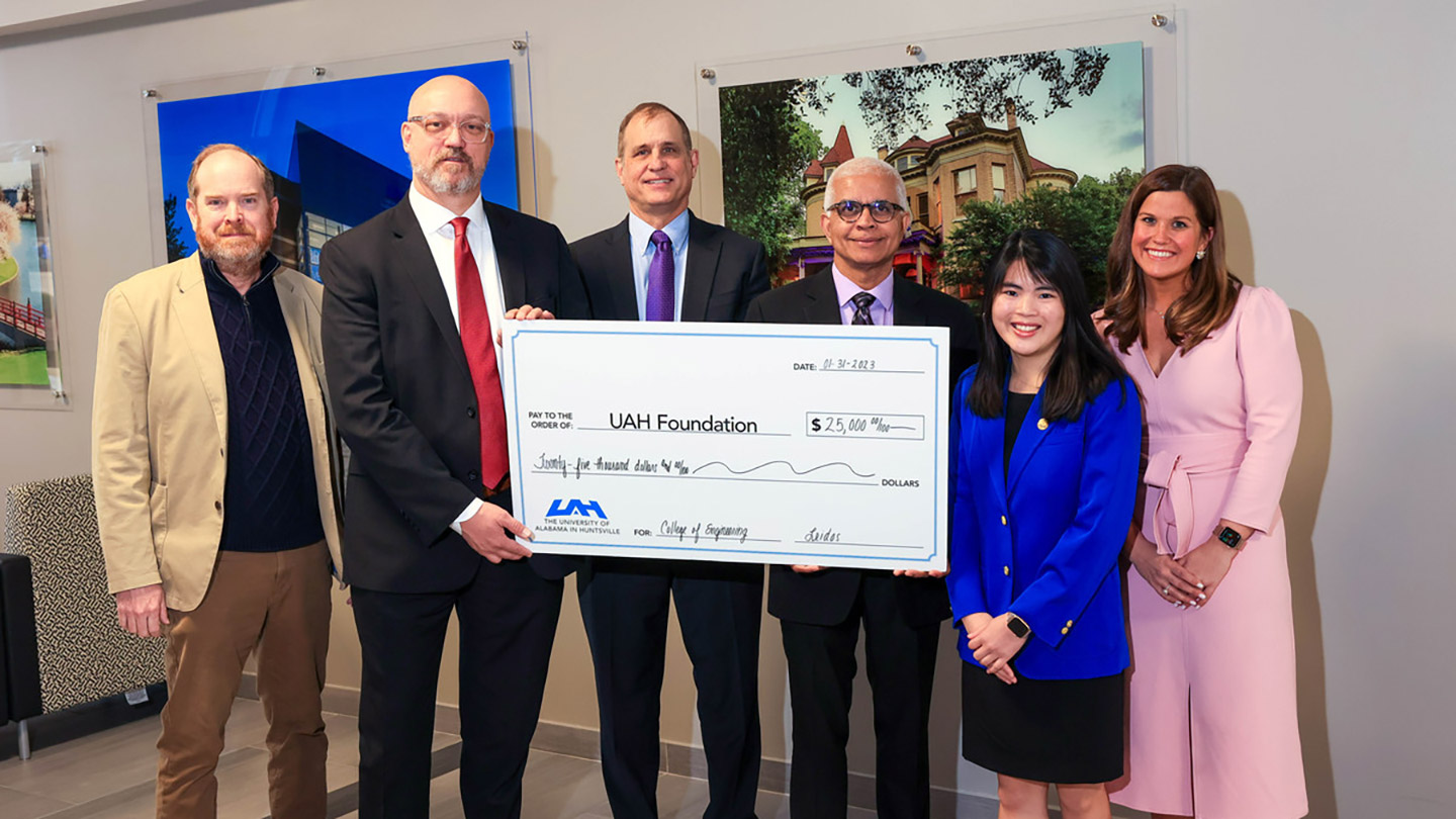 a group of people stand in front of a large check