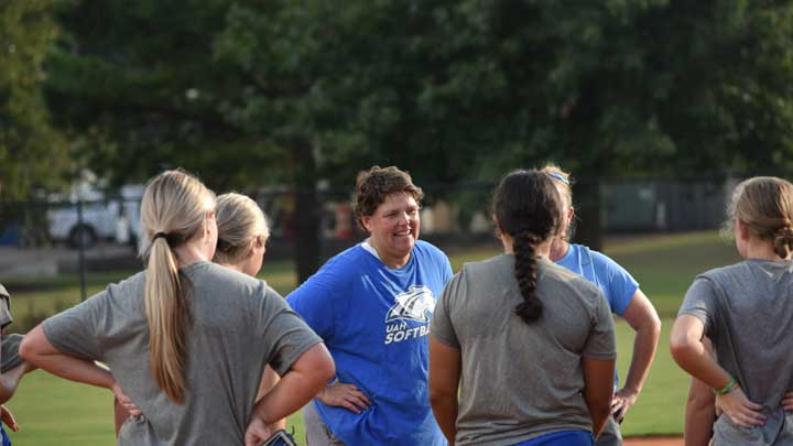 Les Stuedeman, center, founding head softball coach at The University of Alabama in Huntsville, talks to her players.