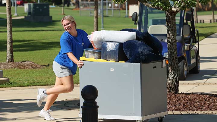 blonde woman pushing a cart of furniture