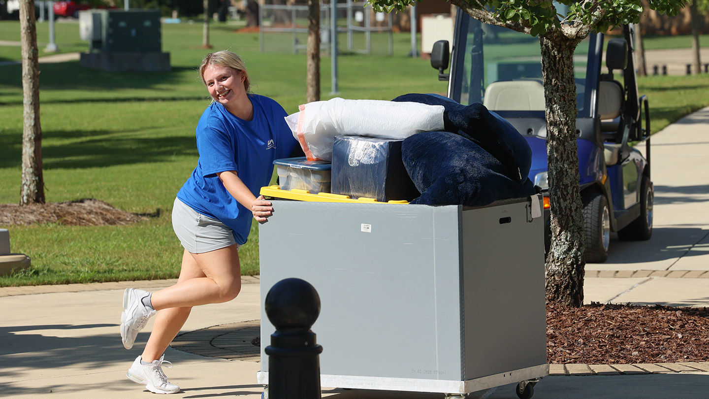 blonde woman pushing a cart of furniture