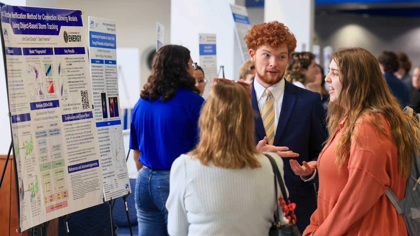 Group of people discussing scientific posters at a conference or academic event in an indoor venue.