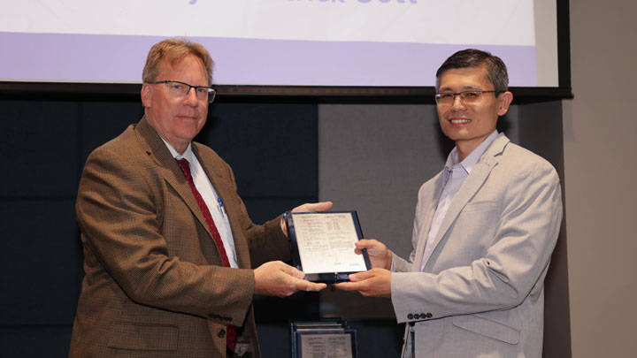 Robert Lindquist, left, congratulates Gabriel Xu for Microplasma-based Heaterless, Insertless Cathode.