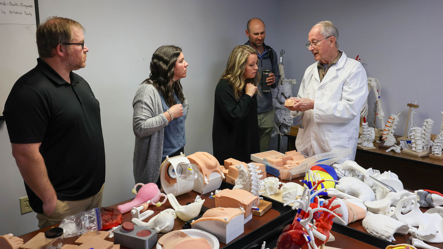 Four teachers from the Albertville City School System learn about the wide range of medical training devices produced by the Model Exchange and Development of Nursing and Engineering Technologies Center from Dr. Bernard Schroer, far right, professor emeritus, College of Engineering,The Albertville teachers are, left to right, Matthew Jackson, Katie Baugh, Anna Frasier and Corbin Holland.