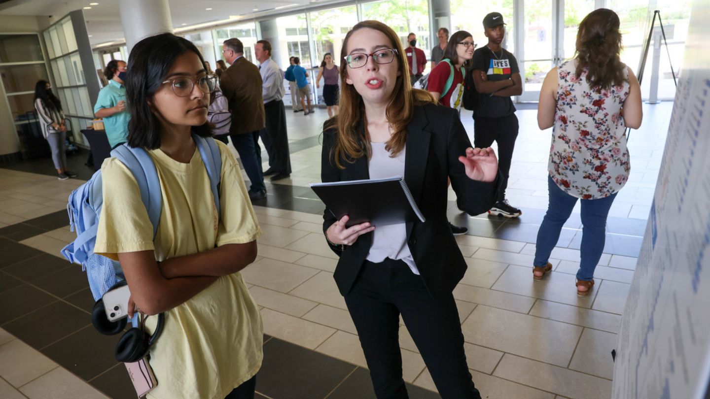 Undergraduate students show and explain their summer research projects in the atrium of the Shelby Center for Science and Technology.