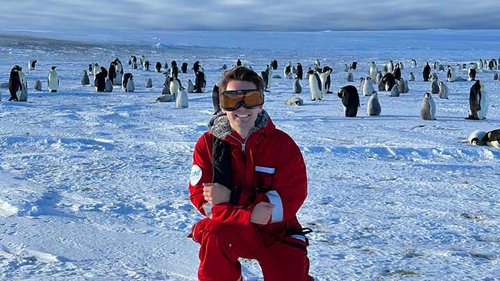Todd McKinney posing in front of a flock of penguins in the Antartic