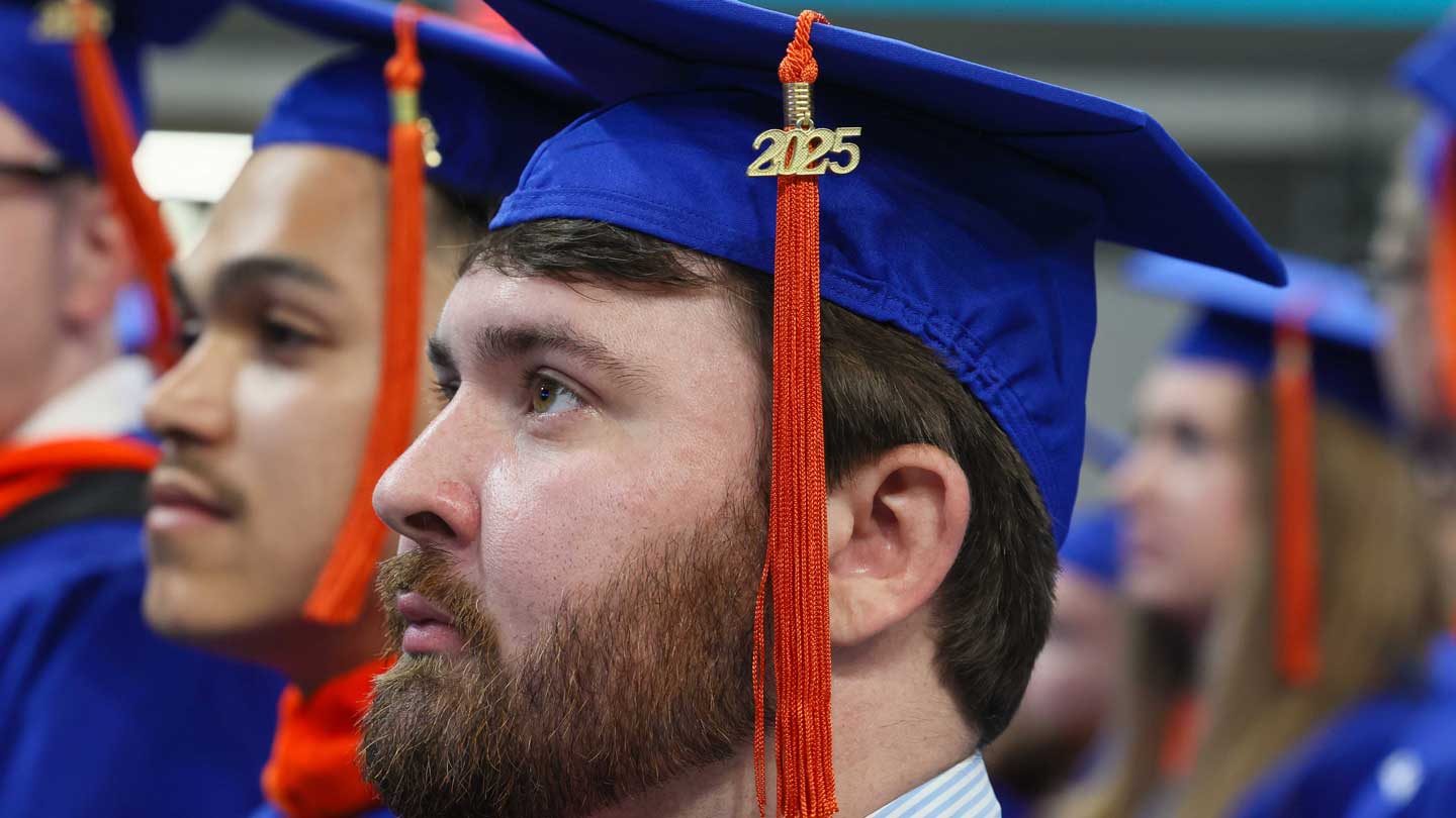 A group of graduates in blue caps and gowns, with a focus on a cap adorned with a '2025' tassel, celebrating their achievement.