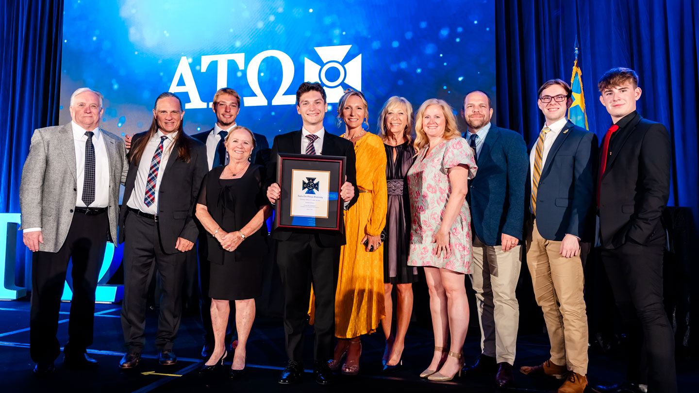 Cadis Ammons, center, a member of the Alpha Tau Omega fraternity’s Theta Pi chapter at The University of Alabama in Huntsville, holds the 2025 Thomas Arkle Clark Award. Surrounding him at the award ceremony, are family members and friends who have become like family to him: from left to right, Rick Ammons, paternal grandfather; Matthew Ammons, father; Nash Ammons, brother; Brenda Ammons, paternal grandmother; Cadis Ammons; Season Ammons, mother; Jackie Head, maternal grandmother; Jill March and Andy March, church family, and Caleb March and Avery March, ATO brothers and church family. The TAC Award was presented at the annual ATO National Award Celebration (NAC 2025) in Miami.