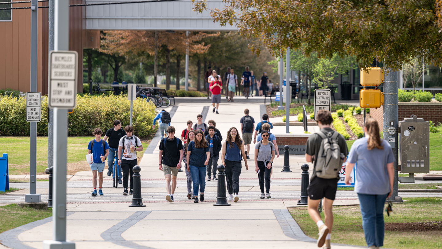 Students walking on a campus pathway with signs about bike regulations.
