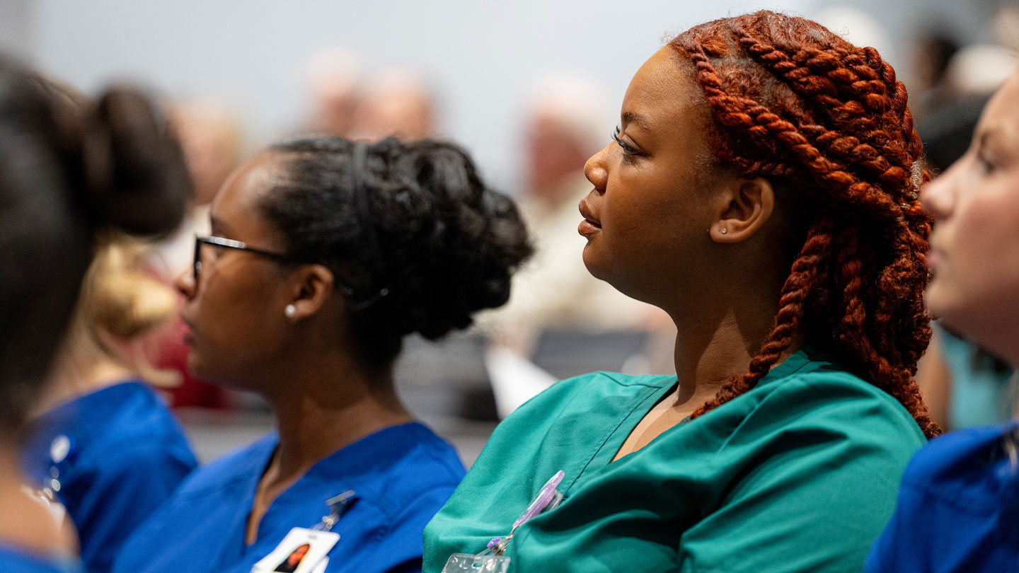 People in medical scrubs attending a conference.